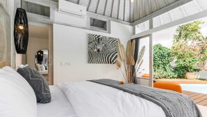Un dormitorio con cama, almohadas, una obra de arte con cebra y vistas al exterior.