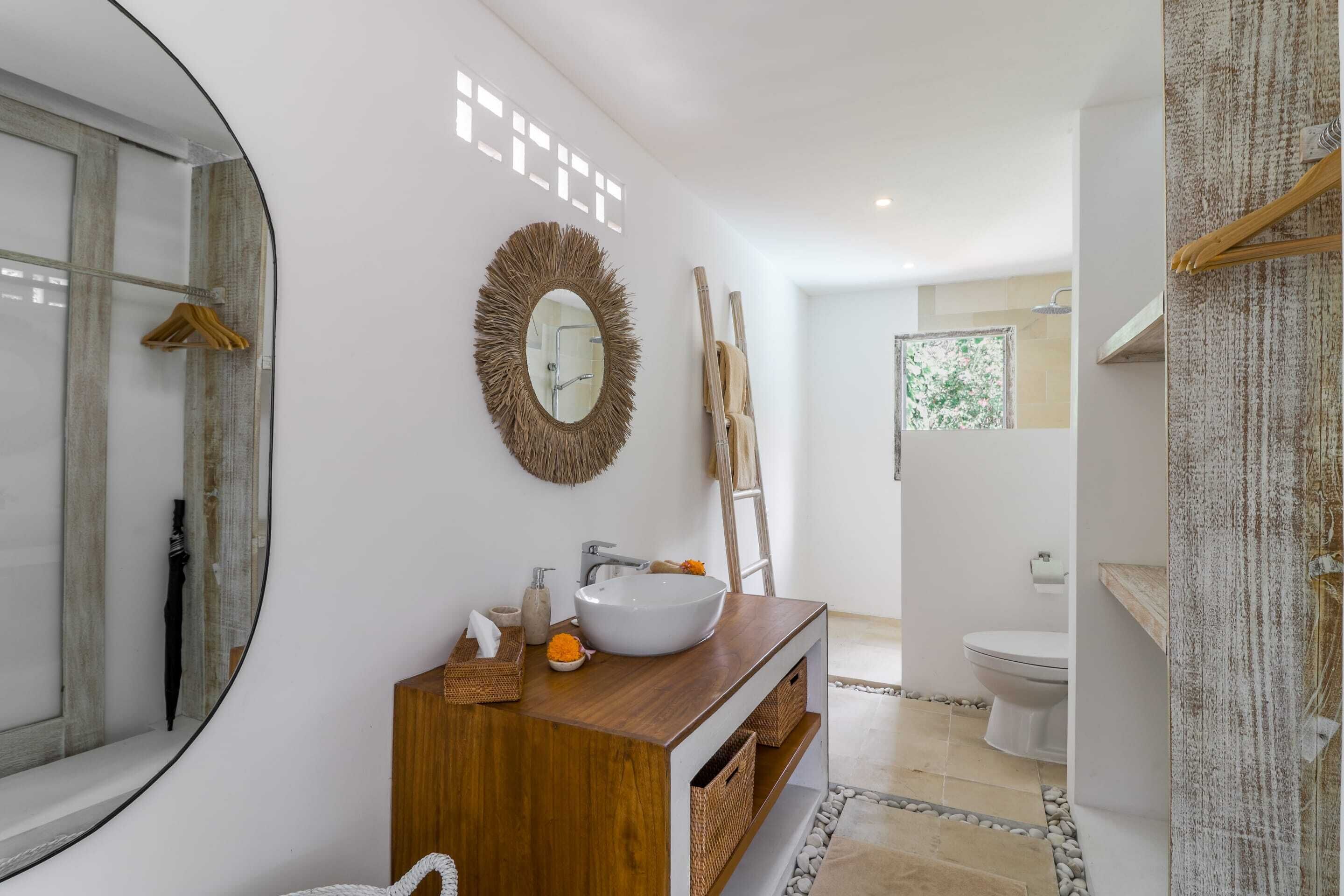 Une salle de bain moderne avec un meuble-lavabo en bois, un grand miroir rond et un grand évier.