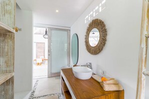 Un baño moderno con tocador de madera, un lavamanos blanco y un espejo con marco decorativo.