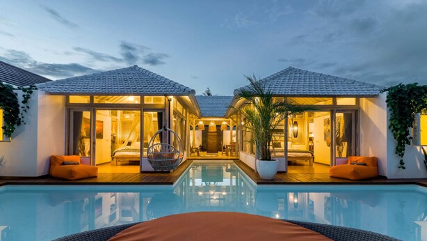 Vista de la piscina de un hotel con dos habitaciones comunicadas, piscina y mobiliario de exterior.