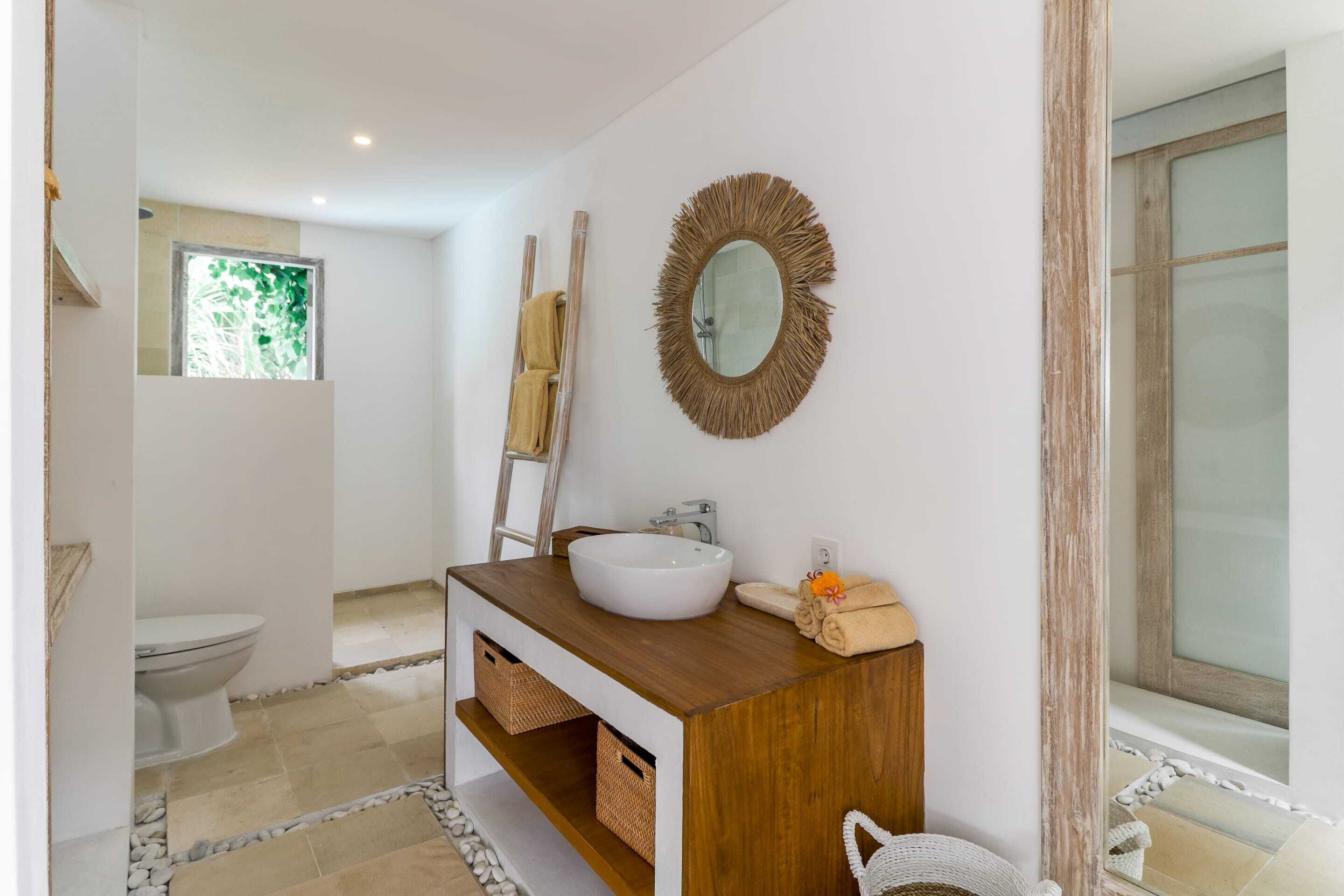 A bathroom with a white sink, wooden vanity, and a mirror.