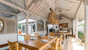 Un comedor amplio con una mesa de madera dispuesta para seis personas, rodeada de sillas de madera.