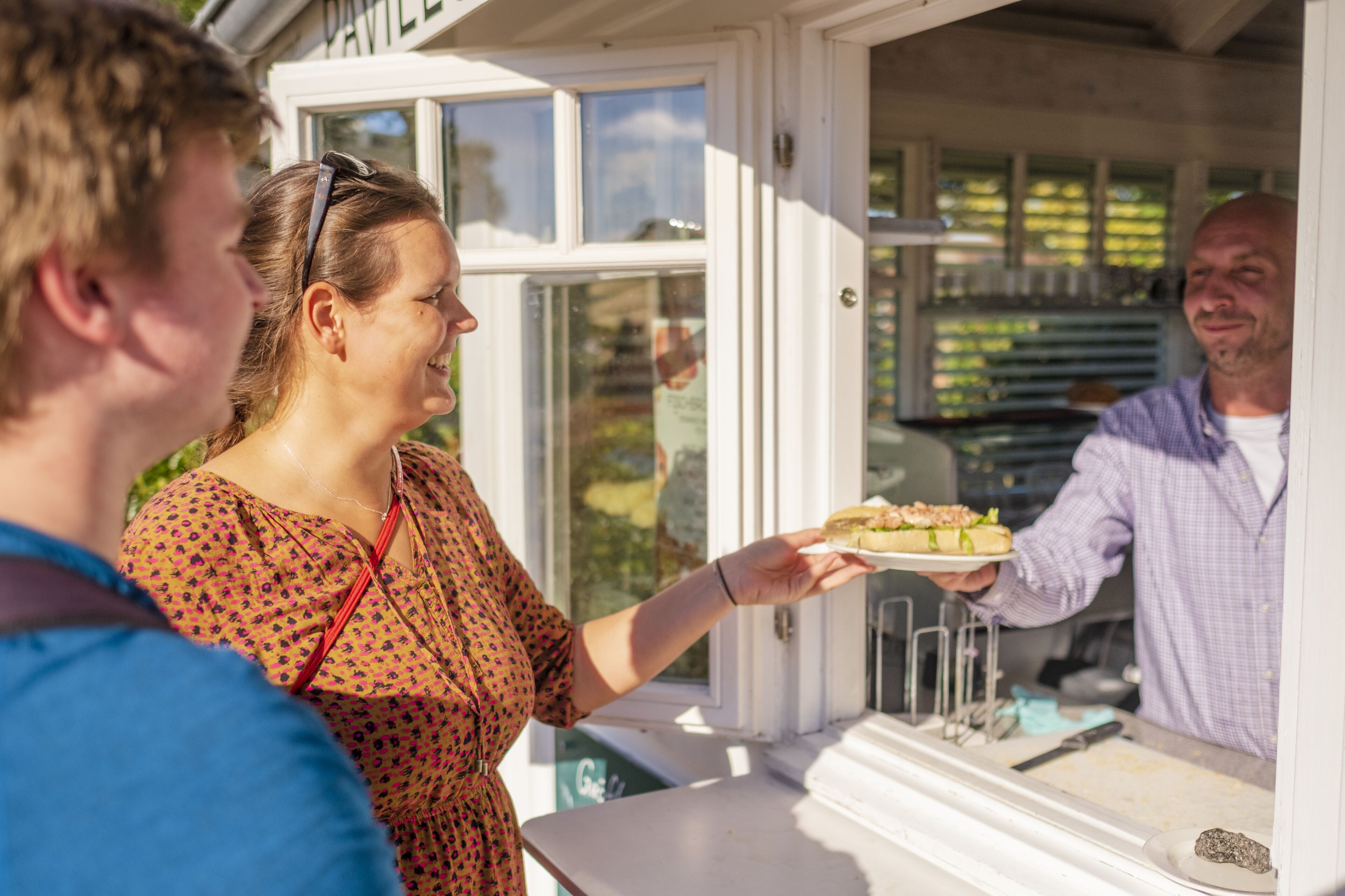 A person holding a plate with food at a counter.