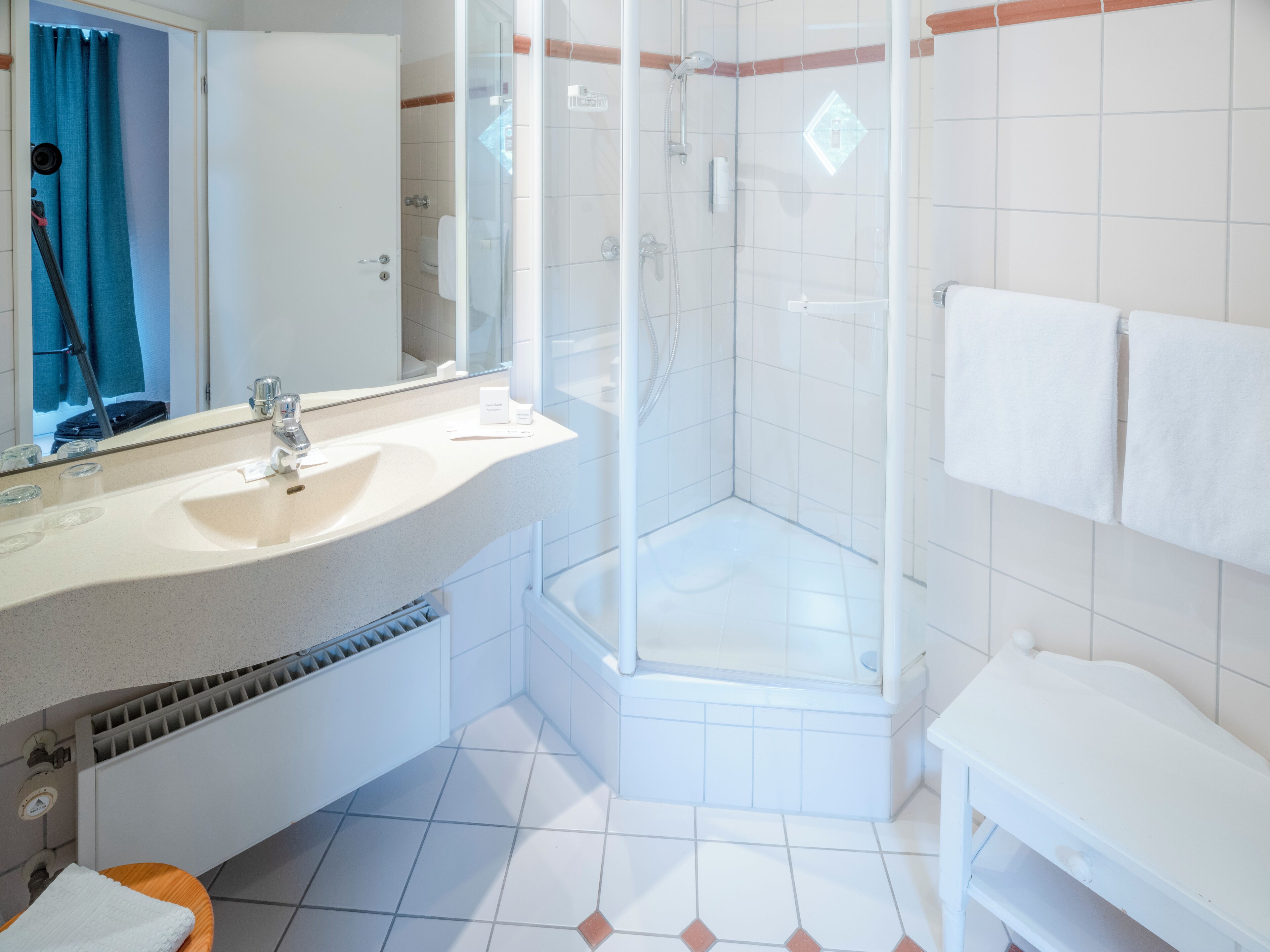 Un baño moderno con lavamanos, espejo, ducha y retrete.