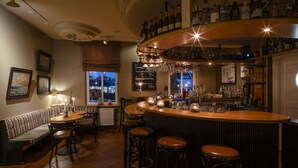 Zona de bar con taburetes, mostrador y una variedad de botellas.
