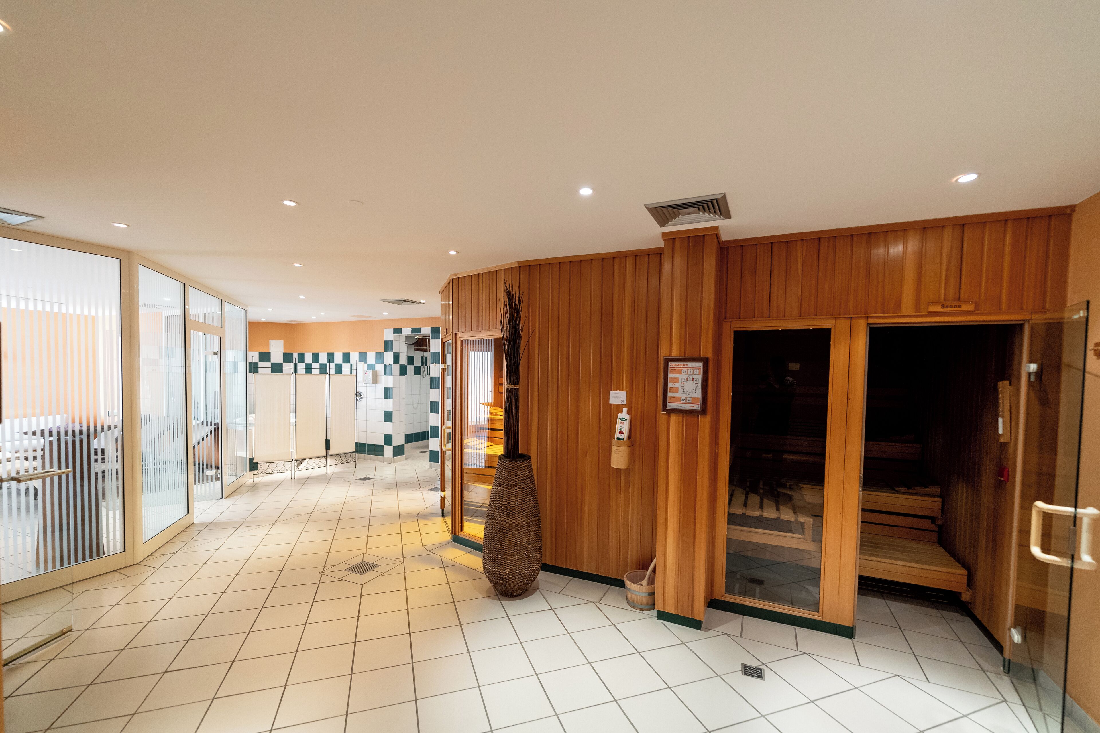 A hotel lobby with a checkered floor pattern, wooden paneling, and a reception area with a large vase.