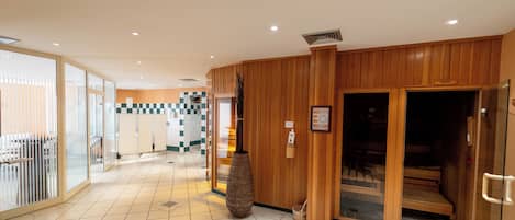 A hotel lobby with a checkered floor pattern, wooden paneling, and a reception area with a large vase.