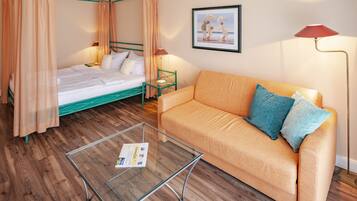 Un dormitorio con cama con dosel, un sofá, una mesita de centro de cristal y un cuadro enmarcado en la pared.