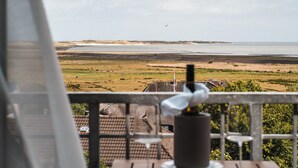 Un balcón con vistas a un paisaje costero, que incluye una playa y una masa de agua.