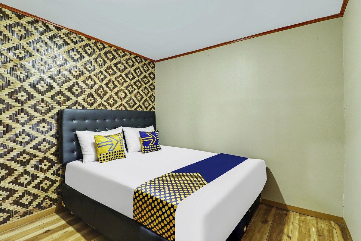 A neatly made bed with a patterned bedspread, a headboard, and decorative pillows.