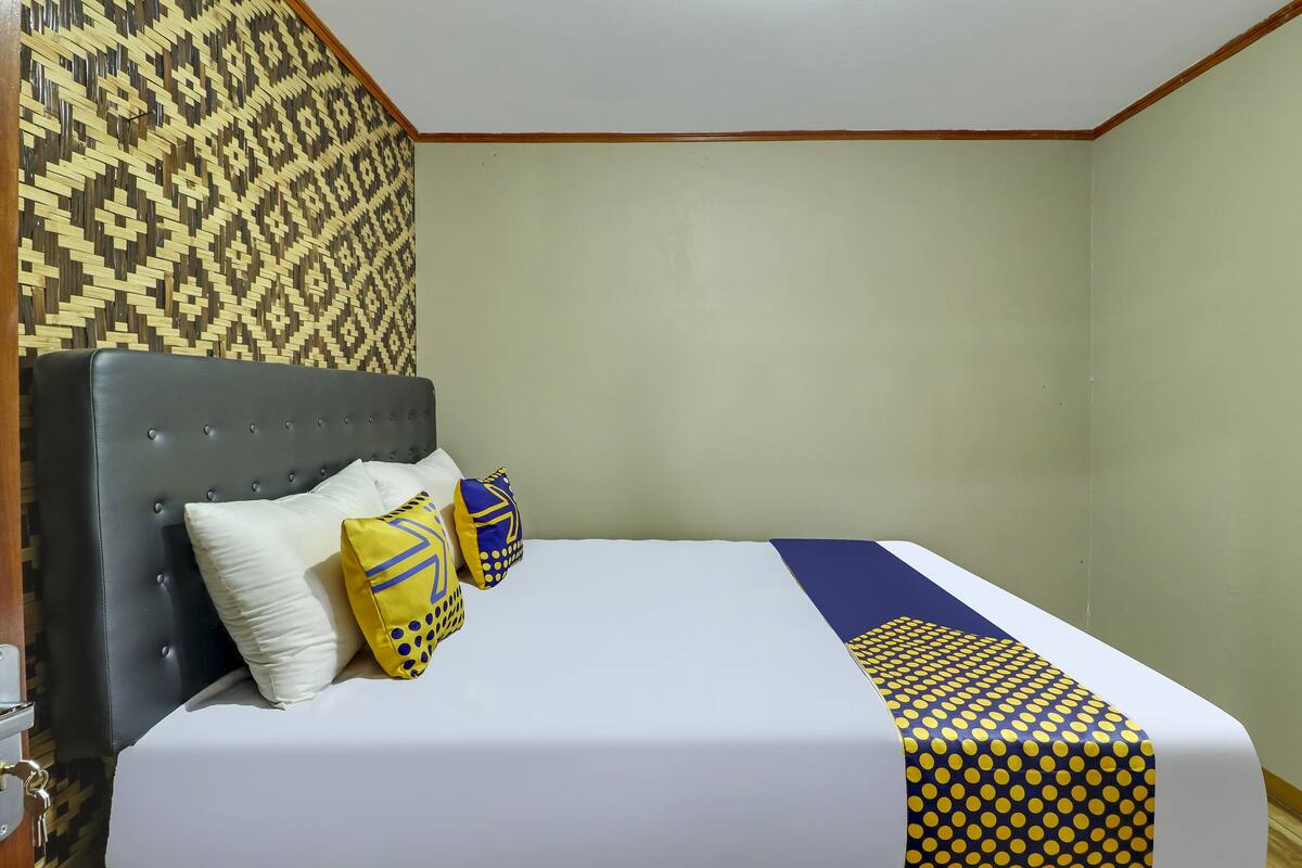 Una habitación de hotel con una cama, un papel tapiz estampado y detalles de madera.