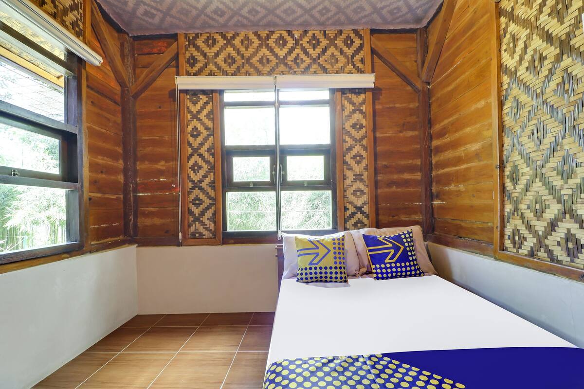 Una habitación con cama, paredes con diseño y una ventana.