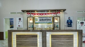 A reception desk with a sign for 'Pemerintahan Desa Guranteng' and framed pictures of individuals. - Hotel O Desa Wisata Guranteng (Guranteng)