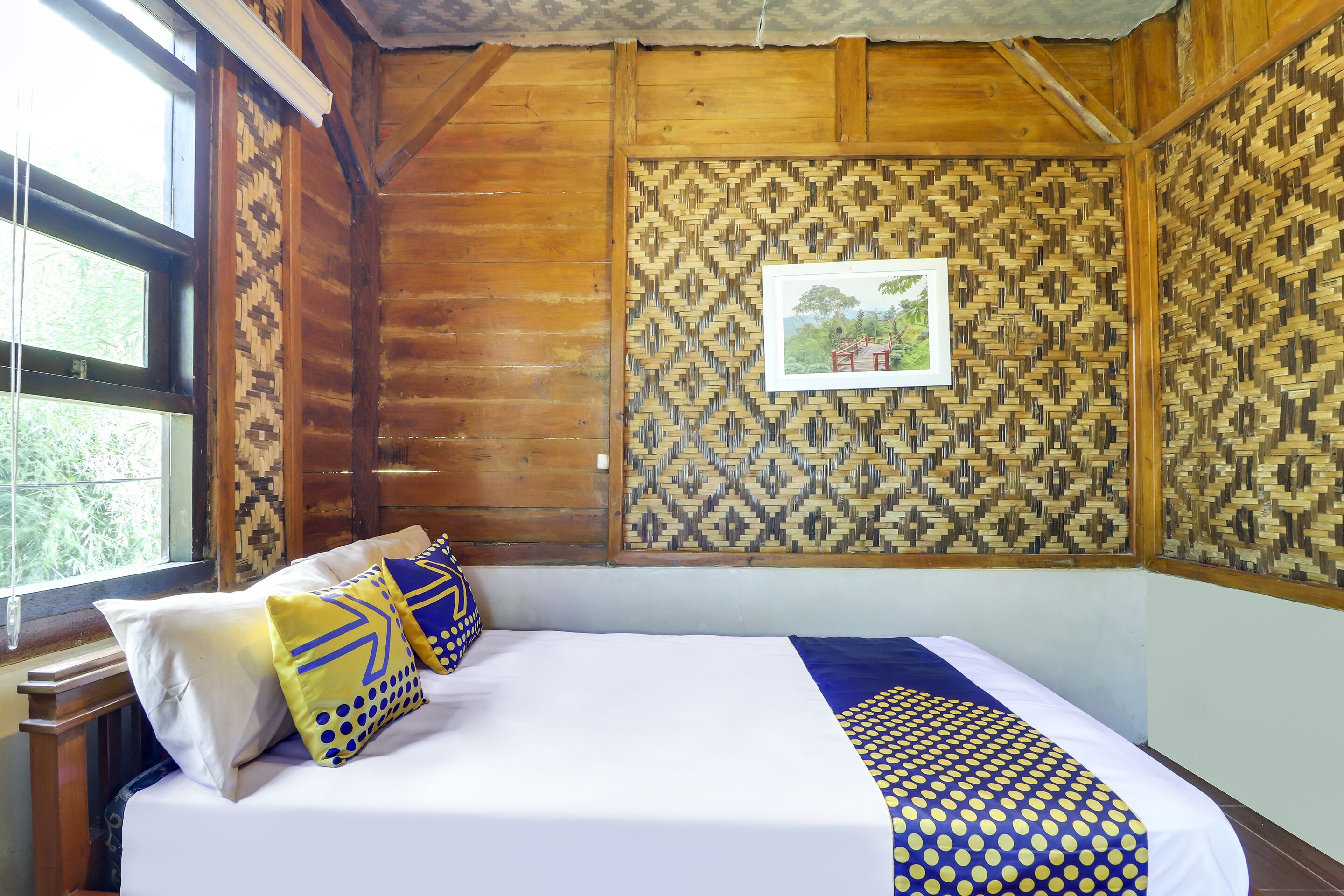 Ein Zimmer in einer Holzhütte mit einem Bett, Kissen und einem gerahmten Bild an der Wand.