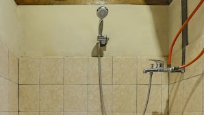 A bathroom with a toilet, a shower, and a visible water pipe. - Hotel O Desa Wisata Guranteng (Guranteng)