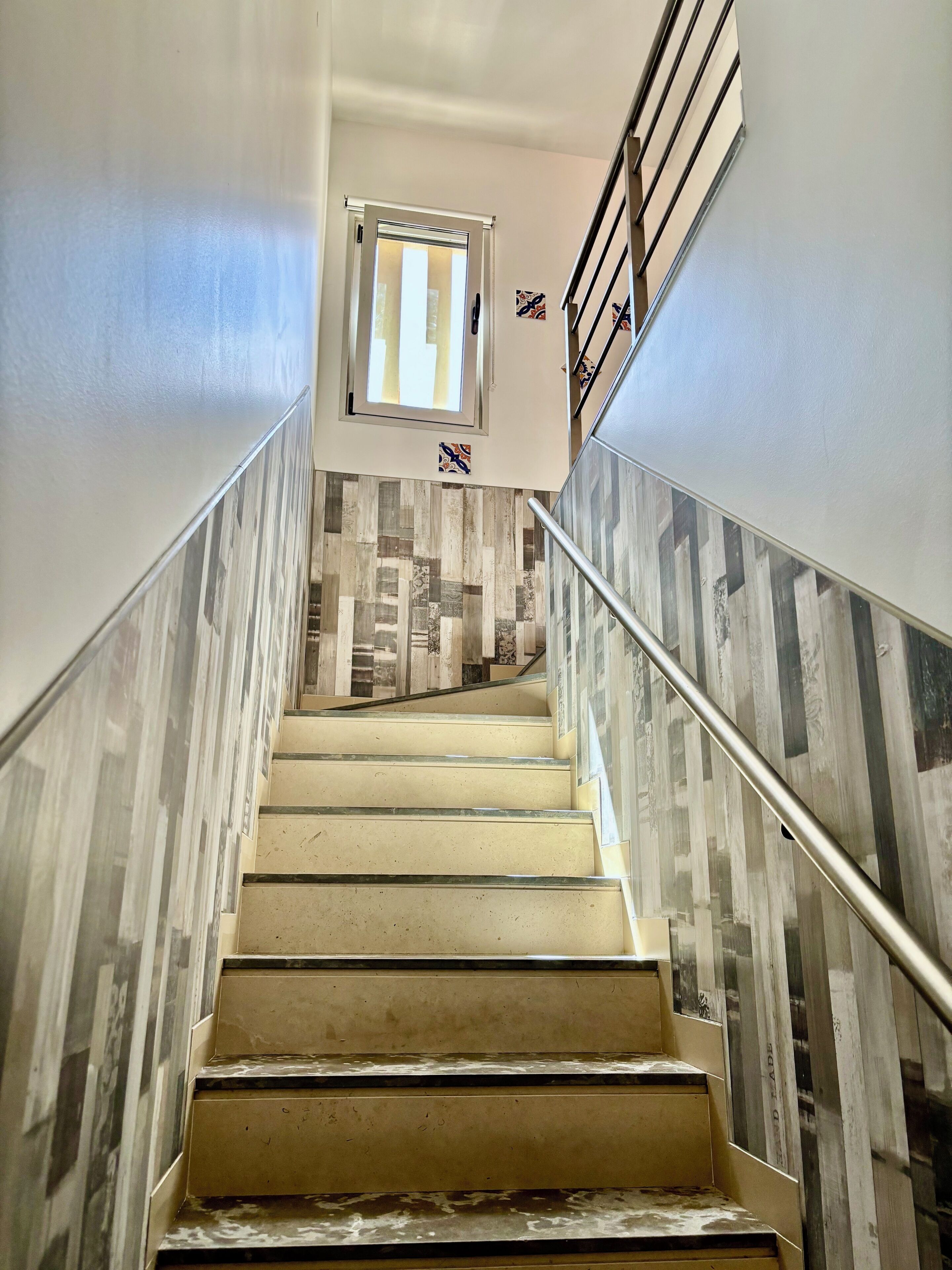 Eine Treppe mit Metallgeländer, einer Wandverkleidung aus Holz und einer Tür mit Fenster oben.