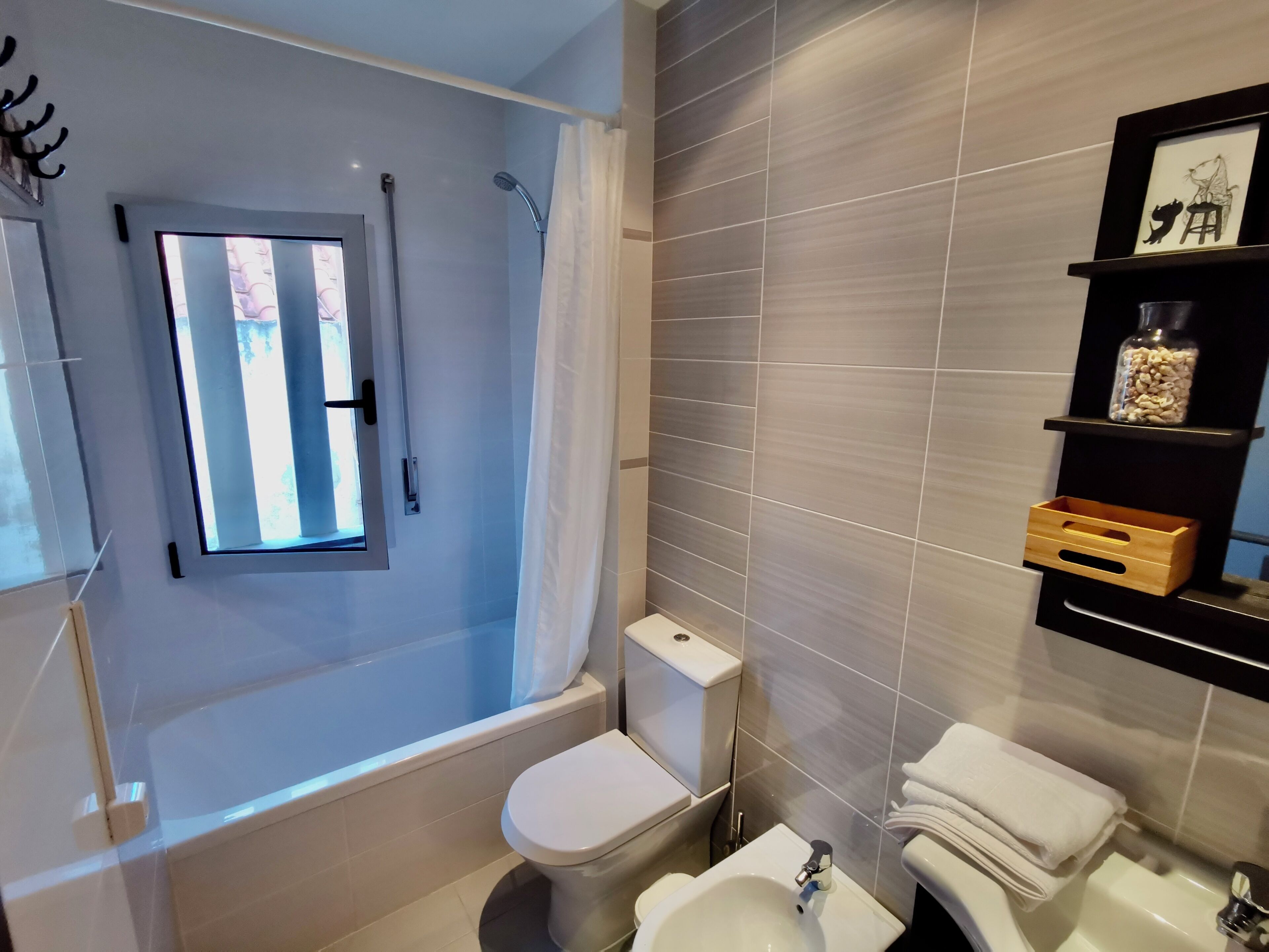 Ein modernes Badezimmer mit Badewanne, Toilette, Bidet und einem Fenster.