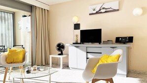 A modern living room with a flat-screen TV, a small fan, and a coffee table.