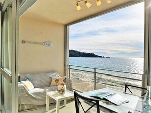 Ein gemütlicher Balkon mit einer Couch, einem kleinen Tisch und Blick aufs Meer.