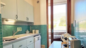 A compact kitchen with a sink, stove, and a table with a toaster.