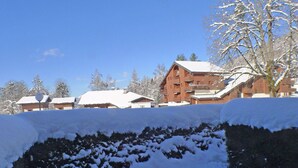 Ett snötäckt landskap med en byggnad som har flera balkonger och ett sluttande tak.