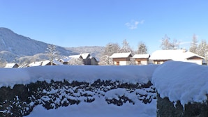 Ett snötäckt landskap med hus och ett berg i bakgrunden.