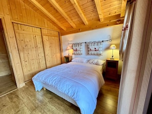 A wooden-paneled bedroom with a bed, two bedside tables, and a headboard with decorative pillows.