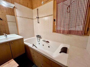 Une salle de bain avec une baignoire, un lavabo et des meubles en bois.