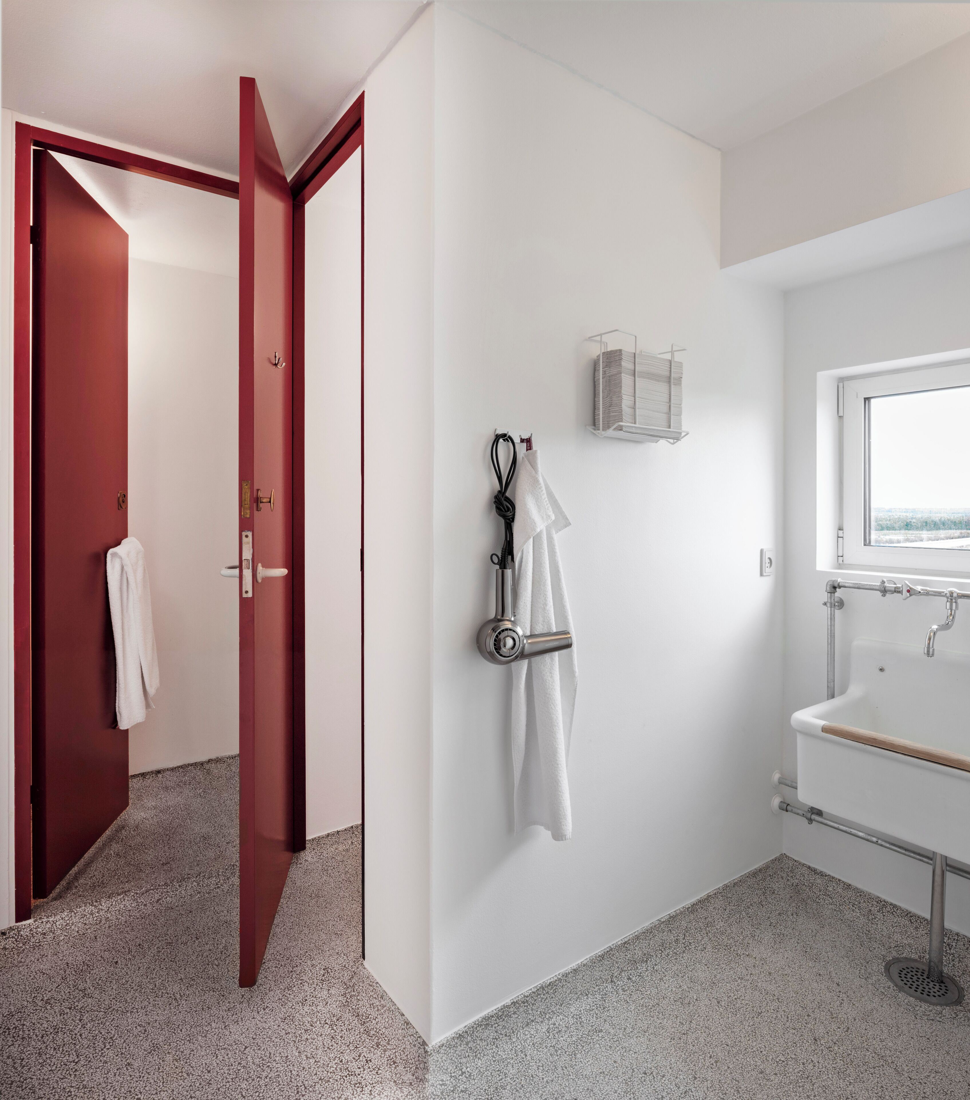Une salle de bain moderne avec un lavabo blanc, une fenêtre et un porte-serviettes.