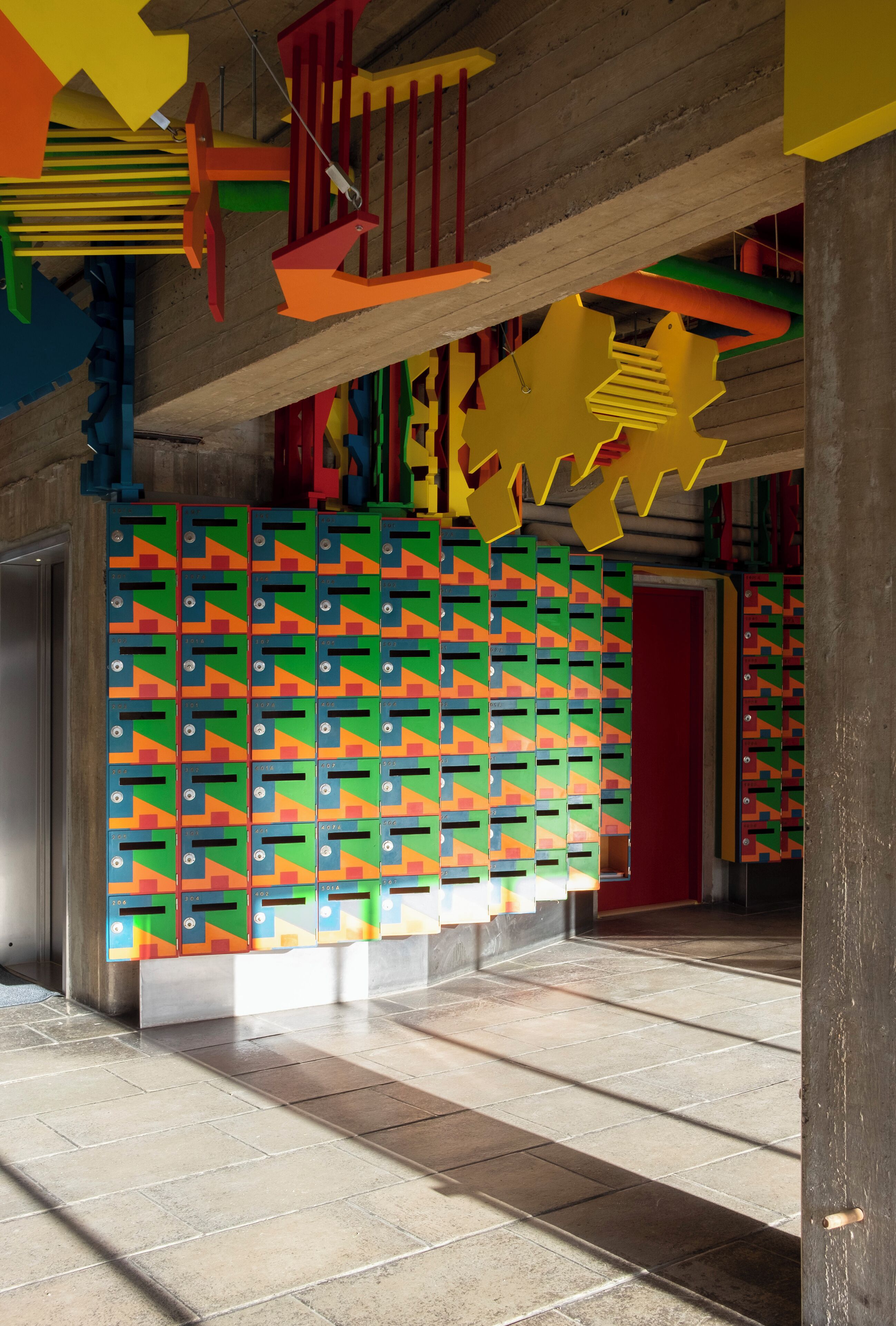 A room with a tiled floor, a red door, and colorful geometric wall decorations.