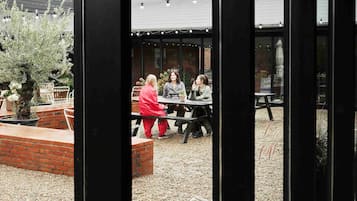 Un espace extérieur aménagé en terrasse, avec un jardin en briques, une table et des chaises.