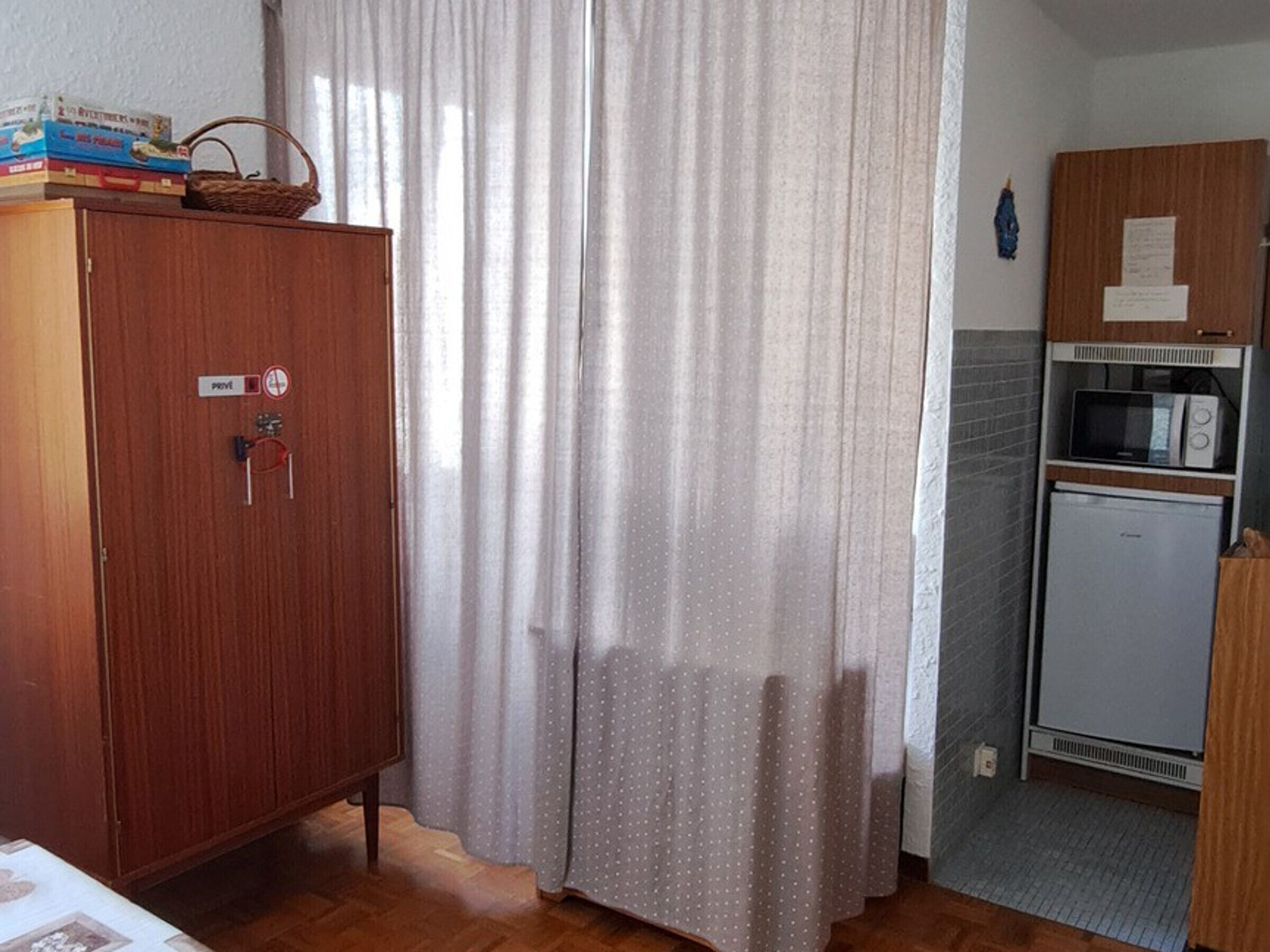 Una cocina compacta con un armario de madera, un microondas y un refrigerador.