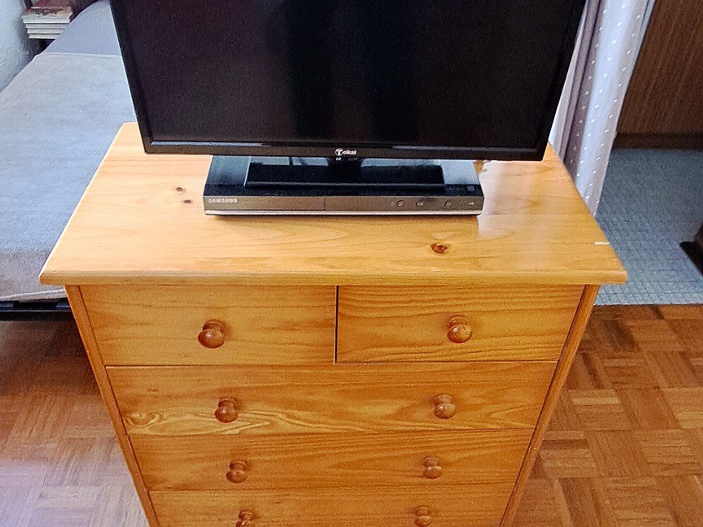 A wooden dresser with a flat-screen TV on top.