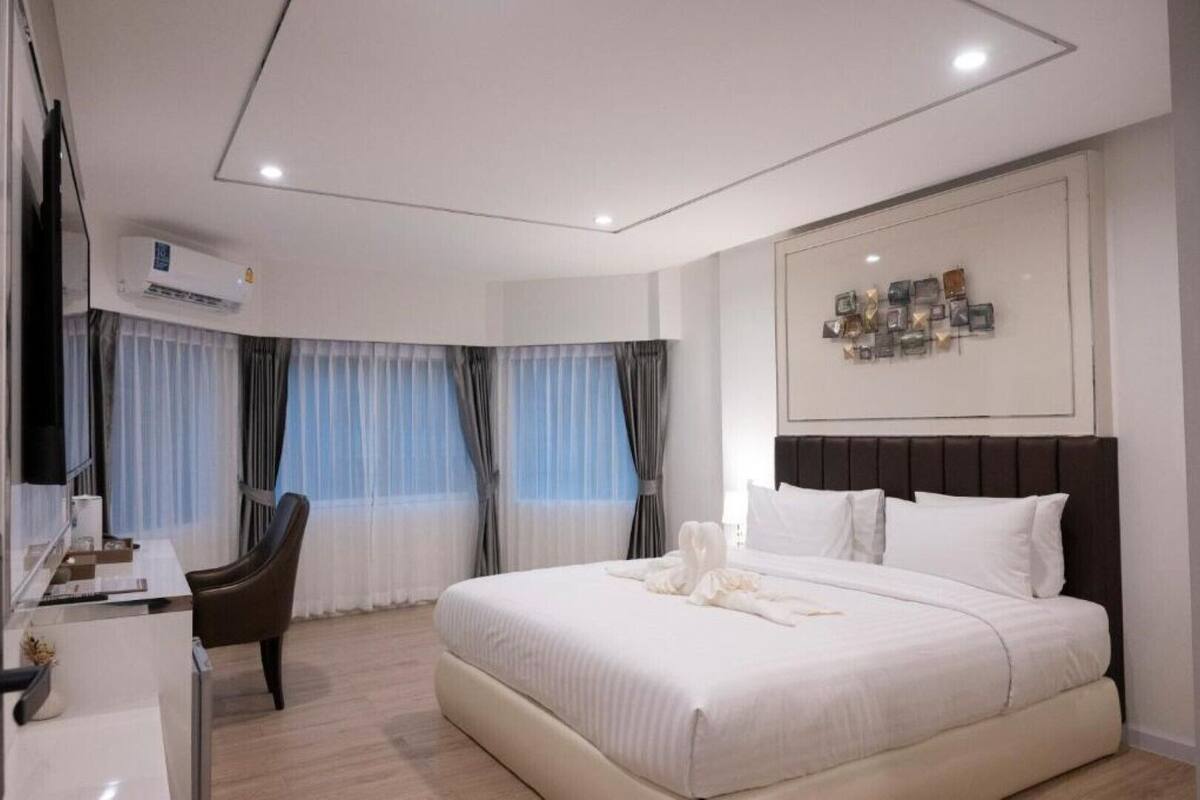A modern hotel room with a large bed, a desk, and a chair.