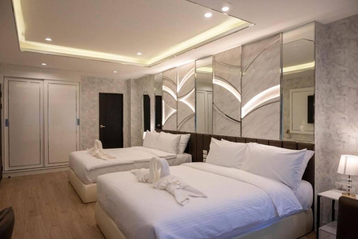A hotel room with two beds, a large mirror, and a wardrobe.