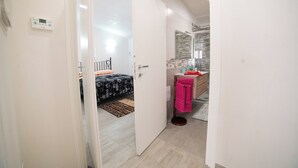 A hotel room with a bed, a bathroom with a mirror, and a door leading to another room.