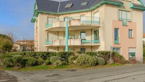 Ein mehrgeschossiges Gebäude mit Balkonen, einer flachen Dachterrasse und einer hellen Fassade.