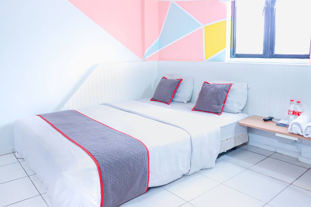 A modern bedroom with a bed, pillows, a bedside table, and a window.