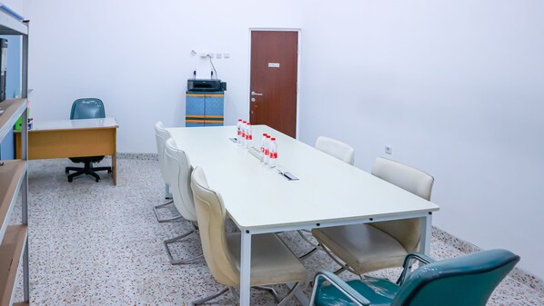 A conference room with a long table, chairs, a printer, and a door labeled "ELEKTRA ROY".
