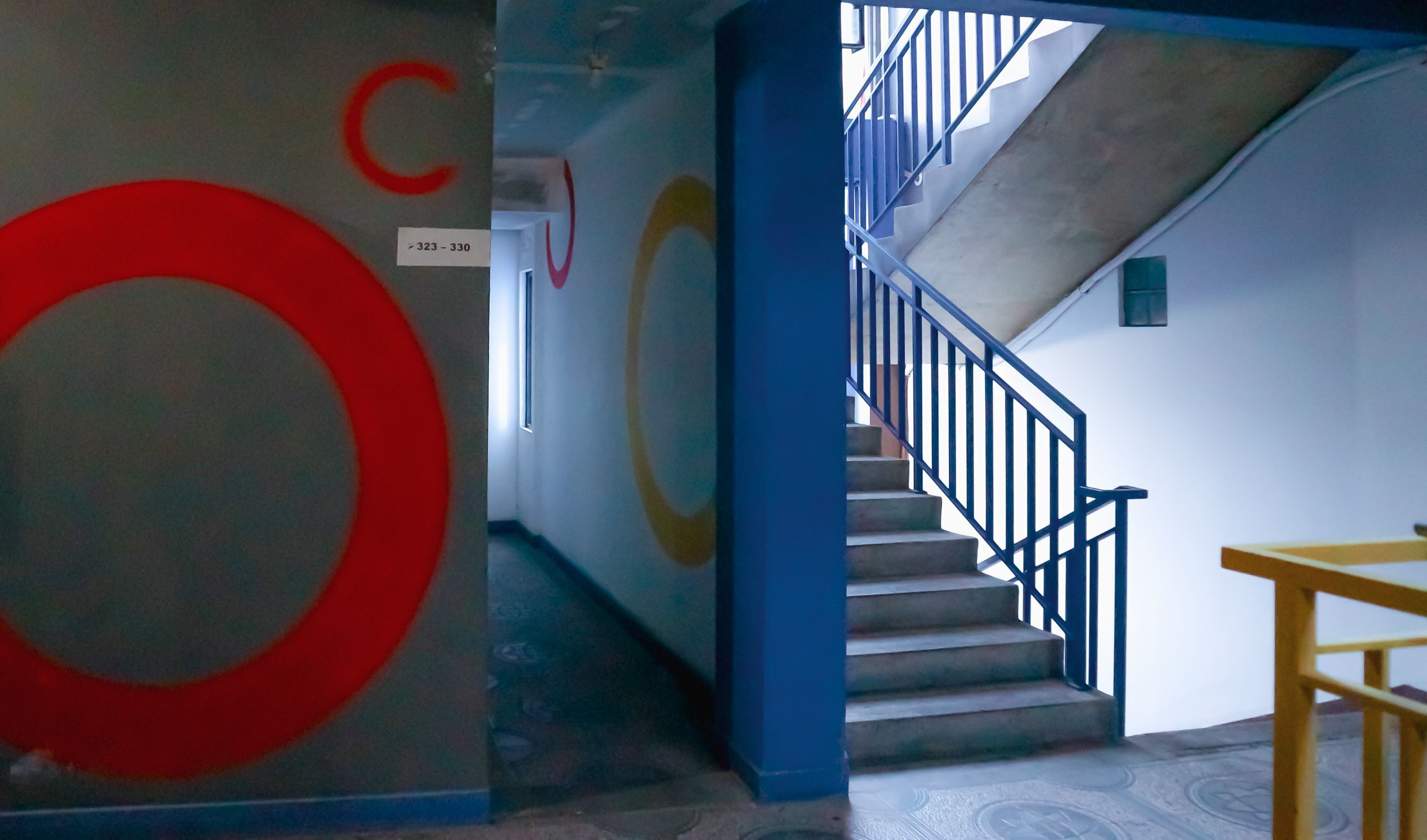 Un escalier avec des rampes bleues menant à l’étage supérieur.