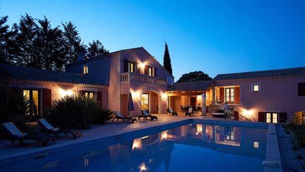 Una casa de dos pisos con piscina, mobiliario exterior y zona de patio.