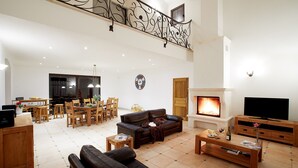 Amplia sala de estar con chimenea, mesa de comedor con sillas, sofá y televisor.