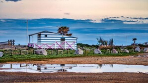 A single-story building with a simple, functional design, situated on a grassy area with a small pond in the foreground. - Cozy Studio Mezzanine with A/C, BBQ, Near Beach & Shops - Sleeps 4, Gruissan (Gruissan)