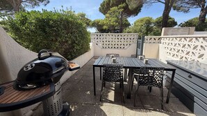 An outdoor patio with a grill, a table, and chairs. - Cozy Studio Mezzanine with A/C, BBQ, Near Beach & Shops - Sleeps 4, Gruissan (Gruissan)