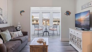 Un salon comprenant un canapé, une table basse, un téléviseur et un balcon offrant une vue sur les immebles.