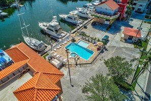 A marina with boats docked, a swimming pool, and a building with a red roof.