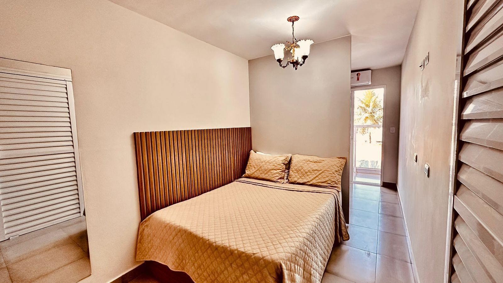 A bedroom with a bed, a chandelier, and a window.