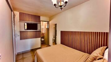 Ein Schlafzimmer mit einem Bett, einem an der Wand montierten Fernseher und einem hölzernen Kopfteil.