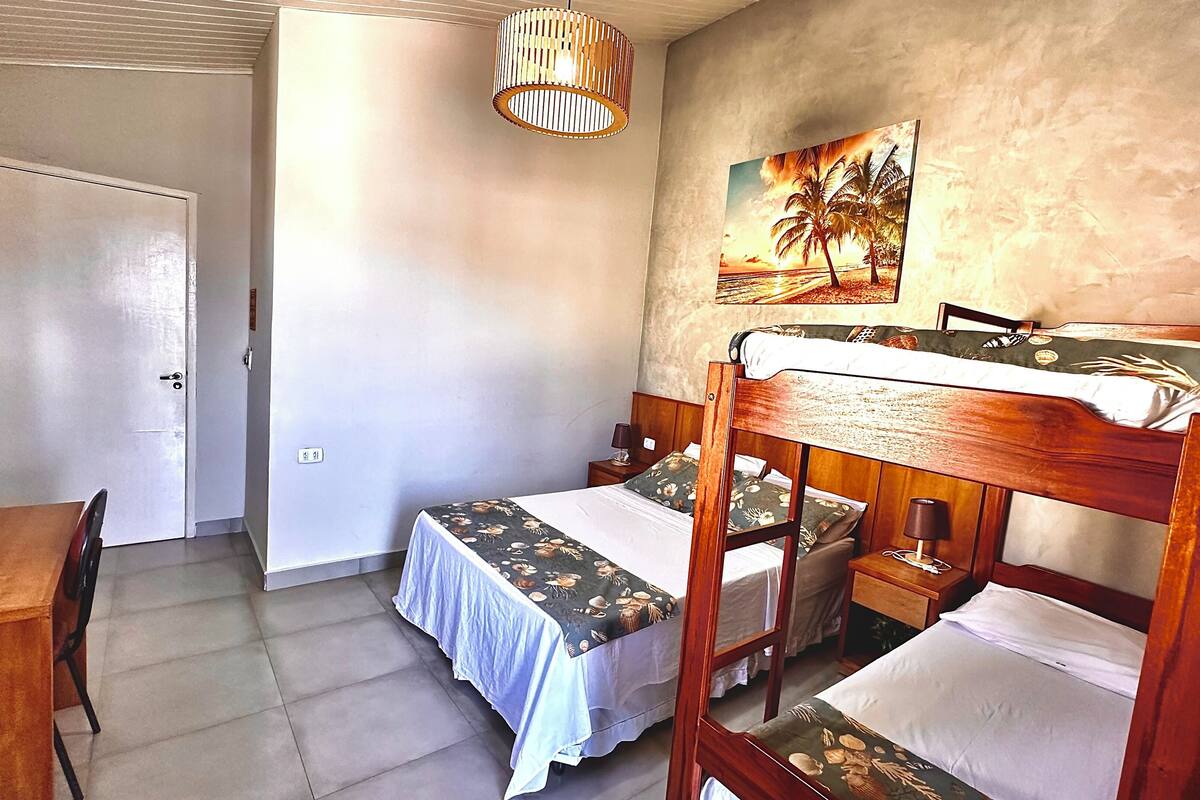 Une chambre avec un lit superposé, un bureau, une chaise, une lampe et un tableau au mur.