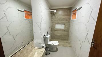Moderni kylpyhuone, jossa on marmoriseinät, puupanelointia koristeena, wc-istuin, pesuallas ja suihku.